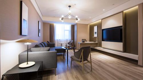 sala de estar con sofá, mesa y TV en Atour Hotel (Houma Xintian Square), en Houma