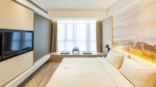 um quarto de hotel com uma cama e uma televisão de ecrã plano em Atour Hotel (Changyang North Road) em Xiangyang