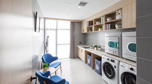 a laundry room with a washer and dryer and blue chairs at Atour Hotel (Changyang North Road) in Xiangyang