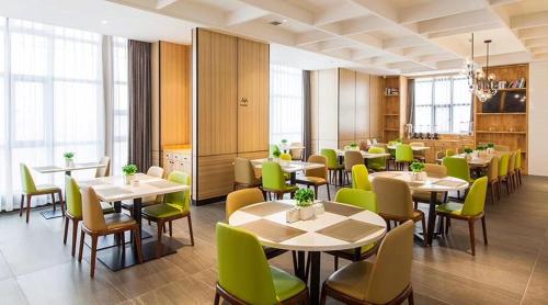 a dining room with tables and green chairs at Atour Hotel (Changyang North Road) in Xiangyang