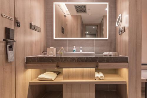 een badkamer met een wastafel en een spiegel bij Atour Hotel (Kong Family Mansion) in Qufu