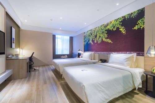 two beds in a hotel room with a painting on the wall at Atour Hotel (Kong Family Mansion) in Qufu
