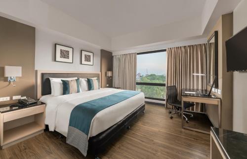 a hotel room with a bed and a desk and a window at Seda Capitol Central Hotel in Bacolod