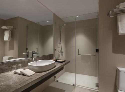 La salle de bains est pourvue d'un lavabo et d'une douche en verre. dans l'établissement Seda Capitol Central Hotel, à Bacolod