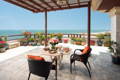 a patio with a table and chairs and the ocean at Anantara Hua Hin Resort in Hua Hin