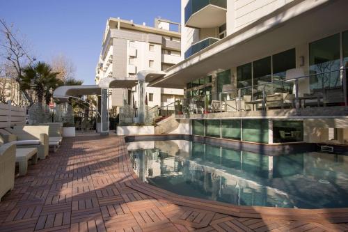 Best Western Maison B Hotel في ريميني: مبنى كبير مع مسبح بجانب مبنى