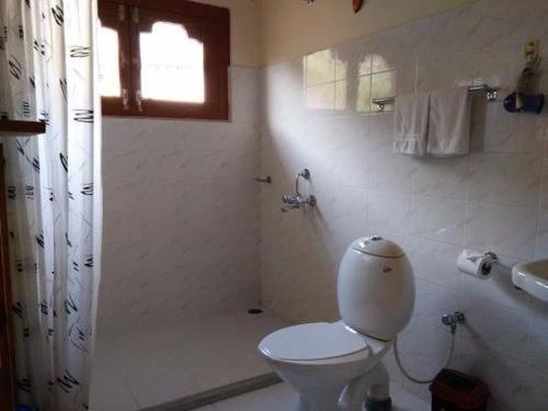 a white bathroom with a toilet and a shower at Nirvana Lodge in Paro