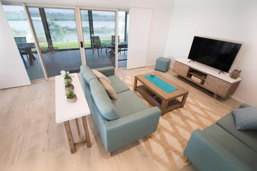 a living room with a blue couch and a tv at ‘Serenity’ and sweeping Murray River views in Tailem Bend