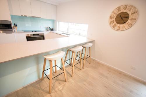a kitchen with white cabinets and a counter with stools at ‘Serenity’ and sweeping Murray River views in Tailem Bend