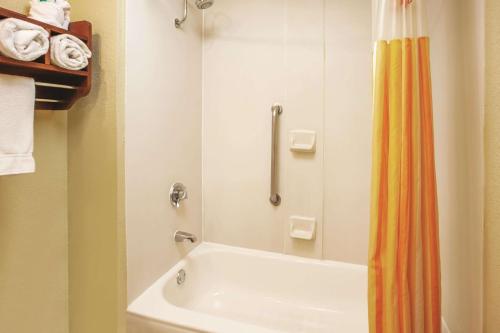 a bathroom with a tub and a shower curtain at Baymont by Wyndham Canton in Canton