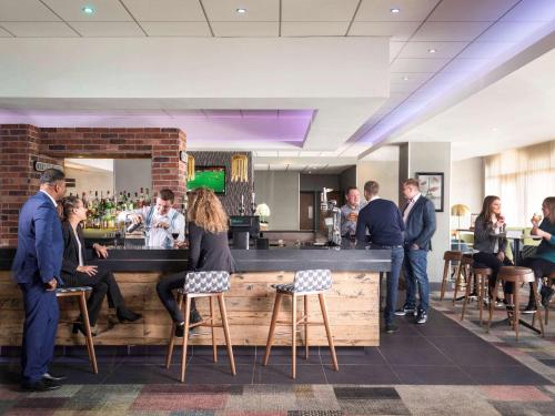 a group of people standing around a bar at Novotel Ipswich Centre in Ipswich