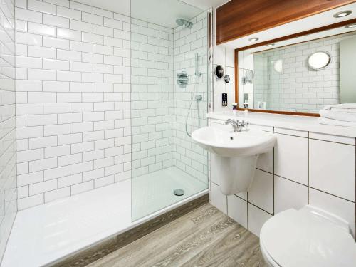 uma casa de banho com um WC, um lavatório e um chuveiro em Mercure Brighton Seafront Hotel em Brighton & Hove