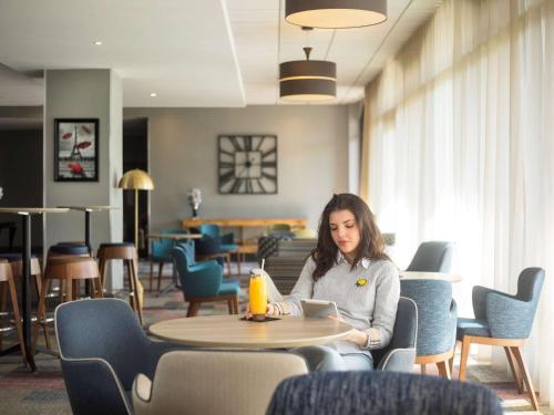 a woman sitting at a table in a restaurant at Novotel Ipswich Centre in Ipswich