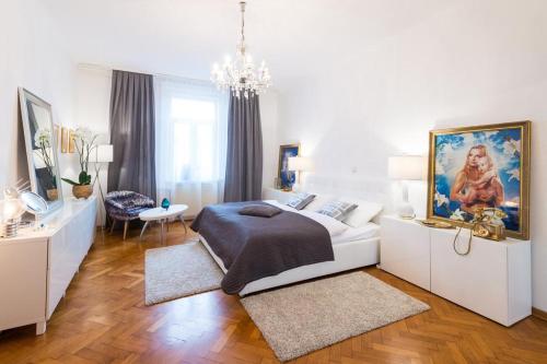 a white bedroom with a large bed and a chandelier at Relax Centar Apartment in Podgorica