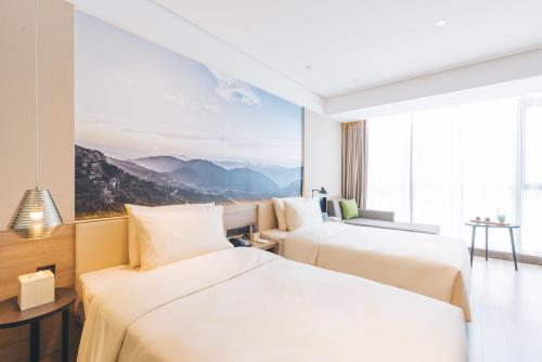 two beds in a hotel room with a mountain view at Atour Hotel Taizhou Linhai Branch in Linhai