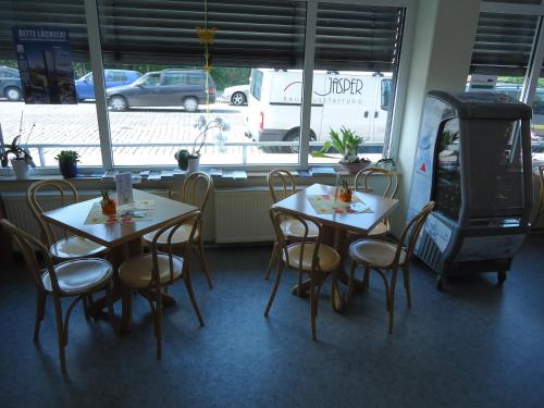 two tables and chairs in a restaurant with a window at Sleep & Go Hotel Magdeburg in Magdeburg