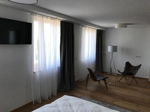 a bedroom with a bed and two chairs and a television at Kallido in Hermeskeil