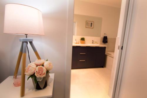 a table with a lamp and a vase of flowers at Contemporary ‘Esprit’ with river reserve access in Tailem Bend