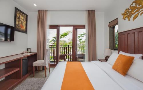 a bedroom with a bed and a desk and a balcony at Won Residence & Spa in Siem Reap