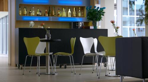 a bar with green and white chairs and a table at Hotel Edda Akureyri in Akureyri