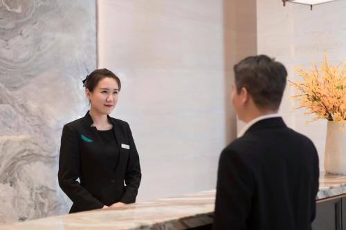 a man and a woman standing next to a counter at Shenyang Huaqiang Novlion Hotel in Daoyi