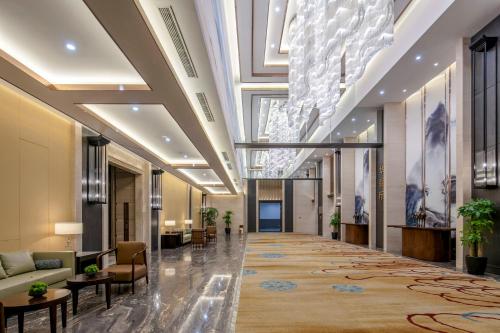 un vestíbulo de un hotel con sofás y mesas en Shenyang Huaqiang Novlion Hotel, en Daoyi