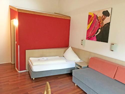ネッカーズルムにあるBrau Art Hotelのベッド1台とソファが備わる小さな客室です。