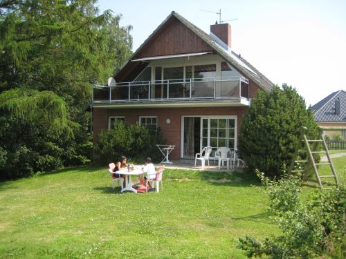 two people sitting at a table in front of a house at Ferienhaus I Weitblick in Grömitz