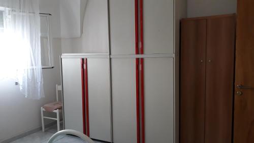 a white refrigerator with red stripes next to a window at casa gialla mare del salento in Maruggio