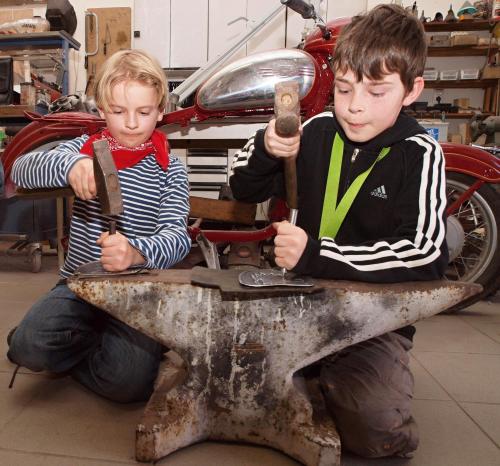 two young boys are working on a table with tools at Penzion statek Bernard in Královské Poříčí