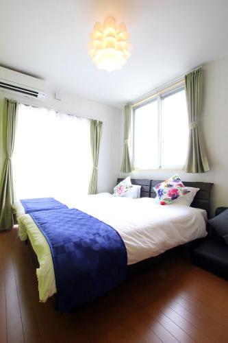 a bedroom with a large bed and two windows at Chura Minpaku Ishigaki in Ishigaki Island