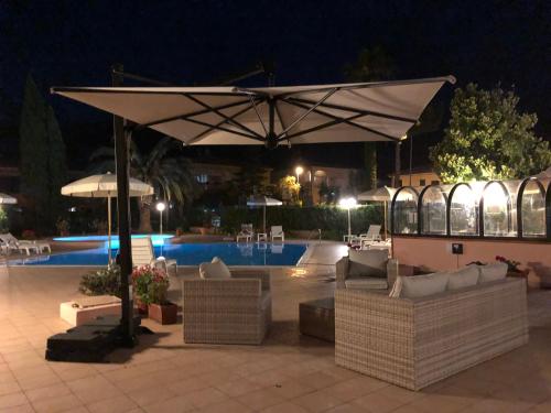 a patio with couches and an umbrella next to a pool at Arthotel Gabbiano Azzurro Due in Marciana Marina