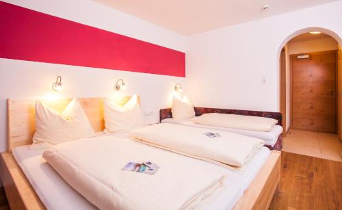 two beds in a room with a red and white wall at Simone's Platzerl - inklusive täglichem freien Eintritt Tauern Spa - nur 5 Gehminuten, Sommerkarte, privatem Garten mit Schwimmteich, Grill und Saunabereich in Kaprun