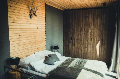 a bedroom with a bed with a wooden wall at Rzepiska Hills in Rzepiska