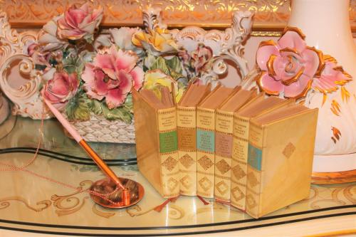 ein Buch auf einem Glastisch neben einem Zauberstab und Blumen in der Unterkunft Fiore d'arancio Luxury City Center Apartment in Verona