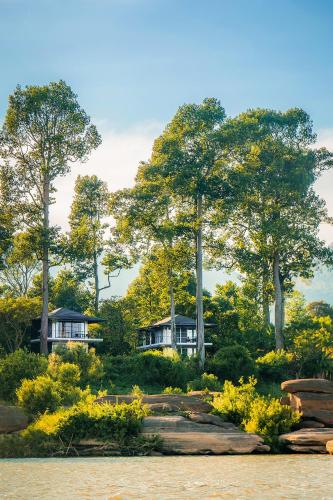 a house in the middle of a garden with trees at The River Resort in Champasak
