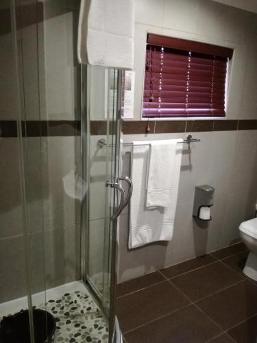 a bathroom with a shower and a toilet and towels at Belmont Guesthouse in Bloemfontein