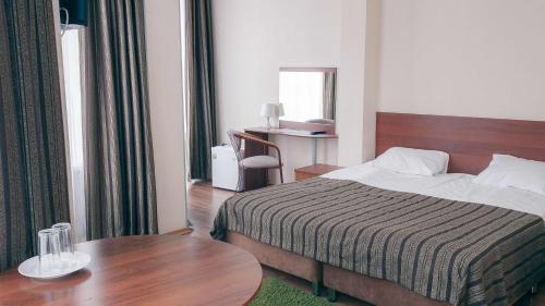 ニジニ・ノヴゴロドにあるAkvarel Hotelのベッドとテーブルが備わるホテルルームです。
