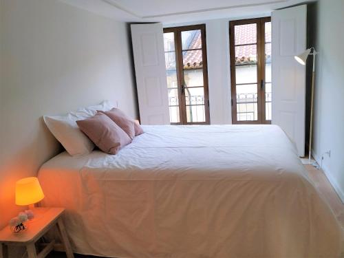a bedroom with a white bed with two windows at Anjo33 Flats in Braga