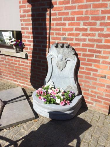 a cement planter with flowers in it next to a brick wall at B&B Don Genaro in Dilsen-Stokkem