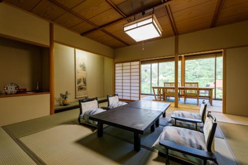 uma sala de jantar com mesa, cadeiras e janelas em Tachibana Shikitei em Kaga
