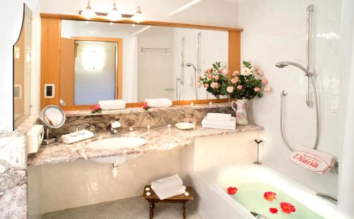 y baño con bañera, lavabo y espejo. en Activehotel Diana, en Siusi