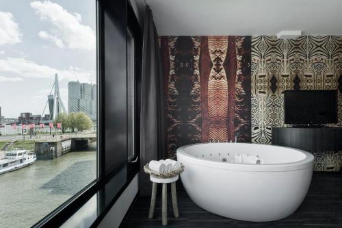 a bath tub in a bathroom with a large window at Mainport Design Hotel in Rotterdam