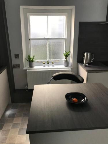una cocina con mesa y una ventana con plantas en The Luxury Apartment, en Buxton