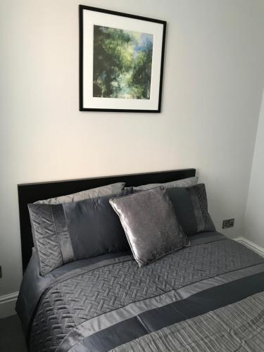 Una cama en un dormitorio con un cuadro en la pared. en The Luxury Apartment, en Buxton