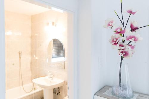 a bathroom with a sink and a vase with pink flowers at Daisy Family Appartment, Vrhnika near Ljubljana in Vrhnika