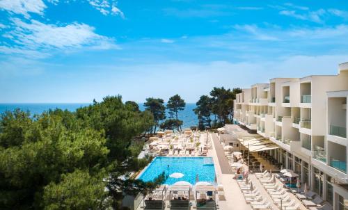 an aerial view of a resort with a pool and chairs at Valamar Carolina Hotel & Villas in Rab