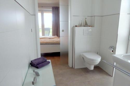 a white bathroom with a toilet and a sink at Apartment Watt´n Glück, Am Alten Deich 26 (Parkplatz 92) in Dangast