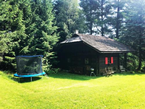 een kleine hut met een blauwe stoel in het gras bij Cozy Log Cabin near Faaker See in Ledenitzen