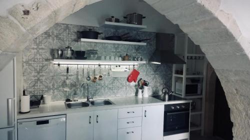 a kitchen with white cabinets and a stone wall at The Manor - Old Town Rethymno, Crete in Rethymno Town